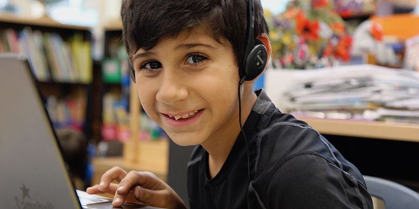 smiling boy with computer and headphones