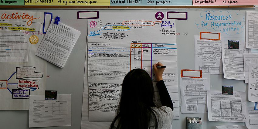 middle school girl writes on a chart describing the plan for a project