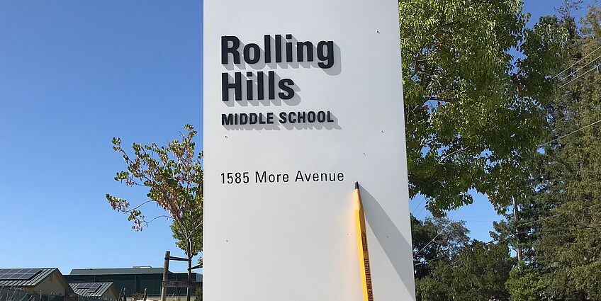 pencil leaning against rolling hills sign