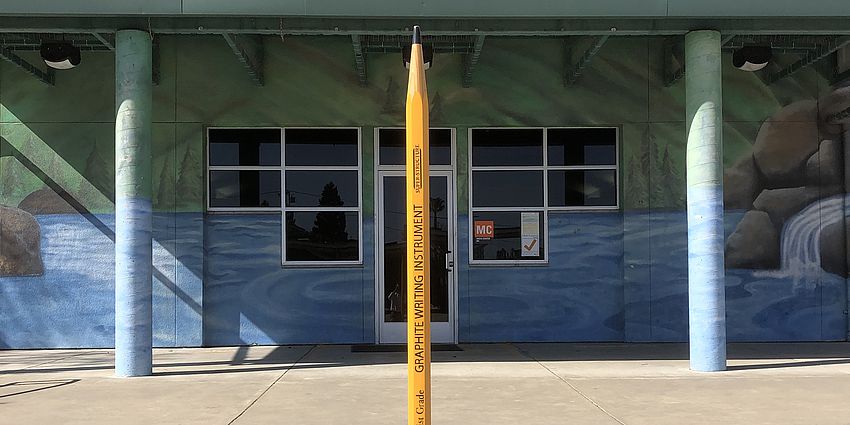 extra large pencil in front of library