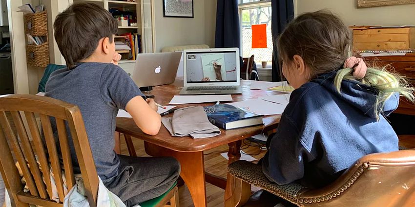 2 students at kitchen table with laptops distance learning