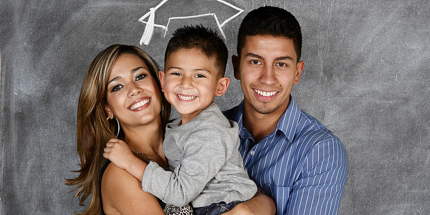 parents hold child with a graduation cap drawn above child's head