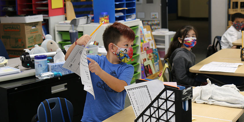 boy holding paper up in class