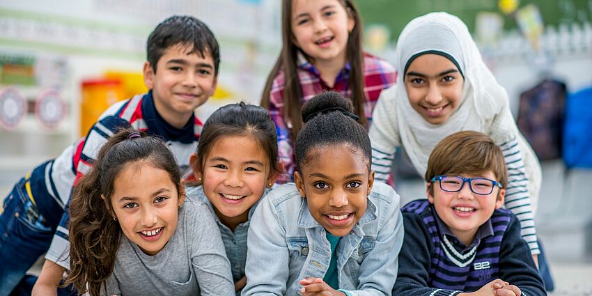 7 children of different ethnicities smiling together in a group