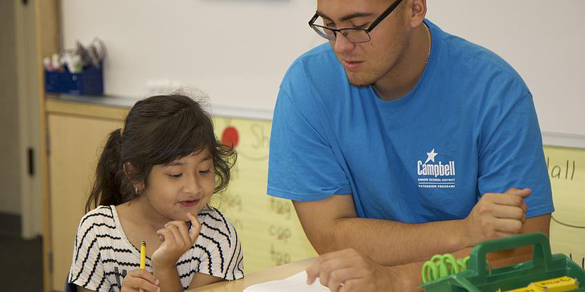 student works on homework with after school staff