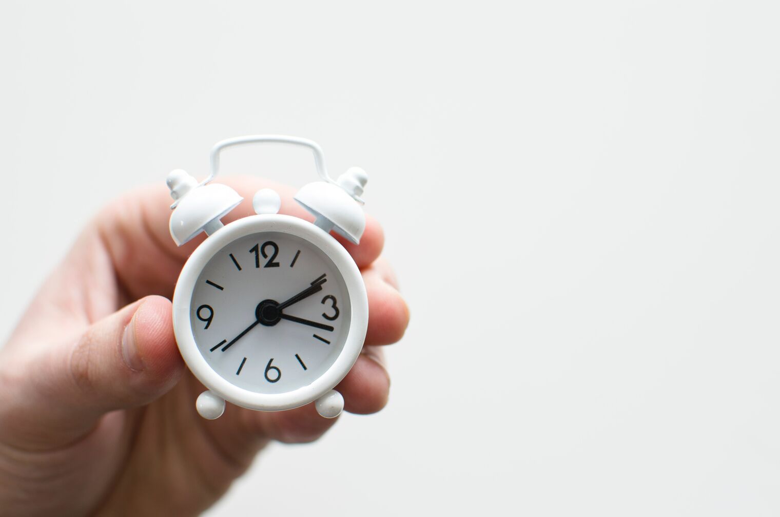 hand holding small alarm clock