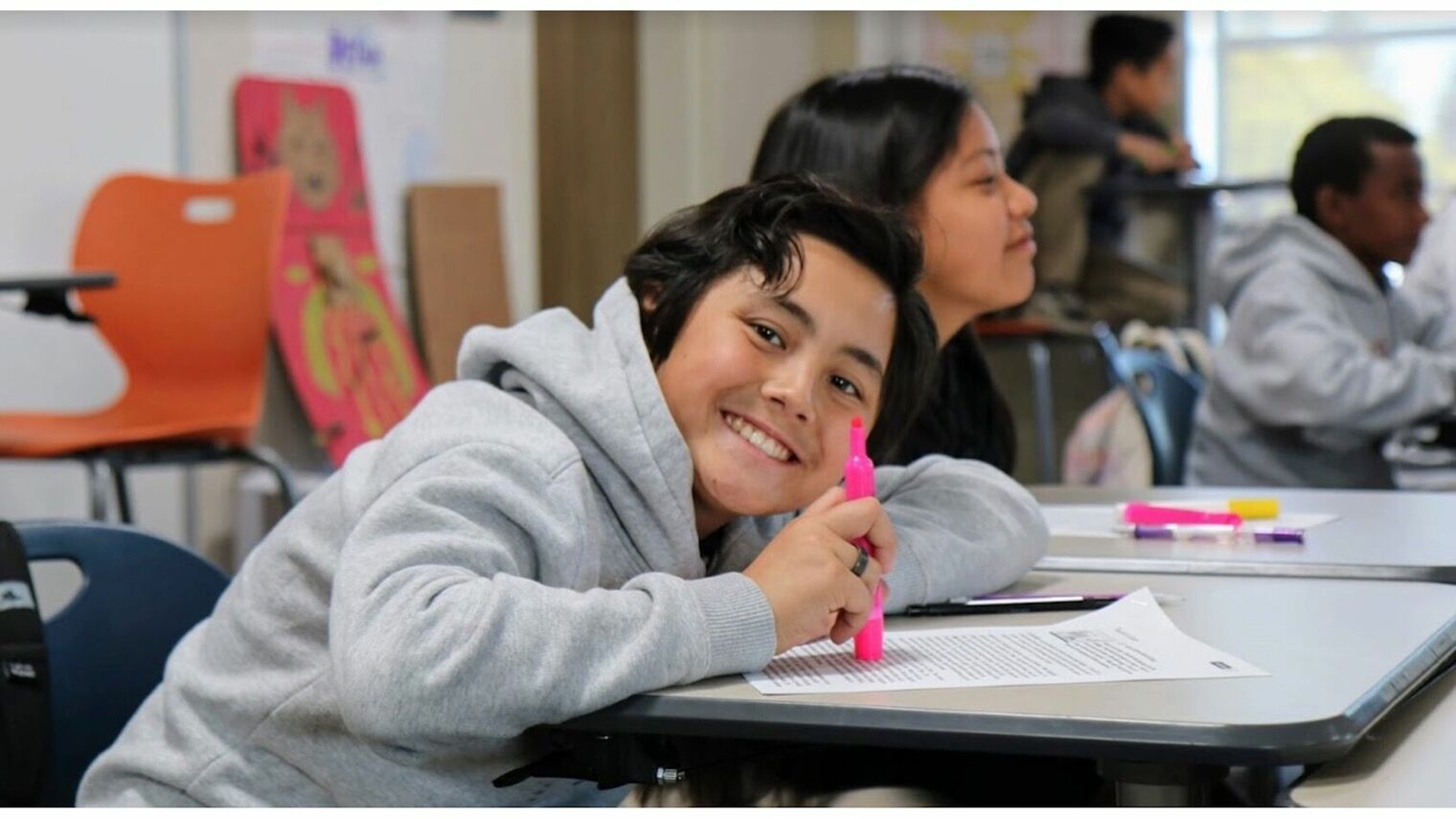 middle school boy smiling and leaning over desk